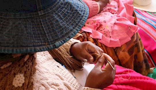 Aymara women in Calamarca skillfully weave and sew, supported by workshops in their local language, increasing their sales by 20%.